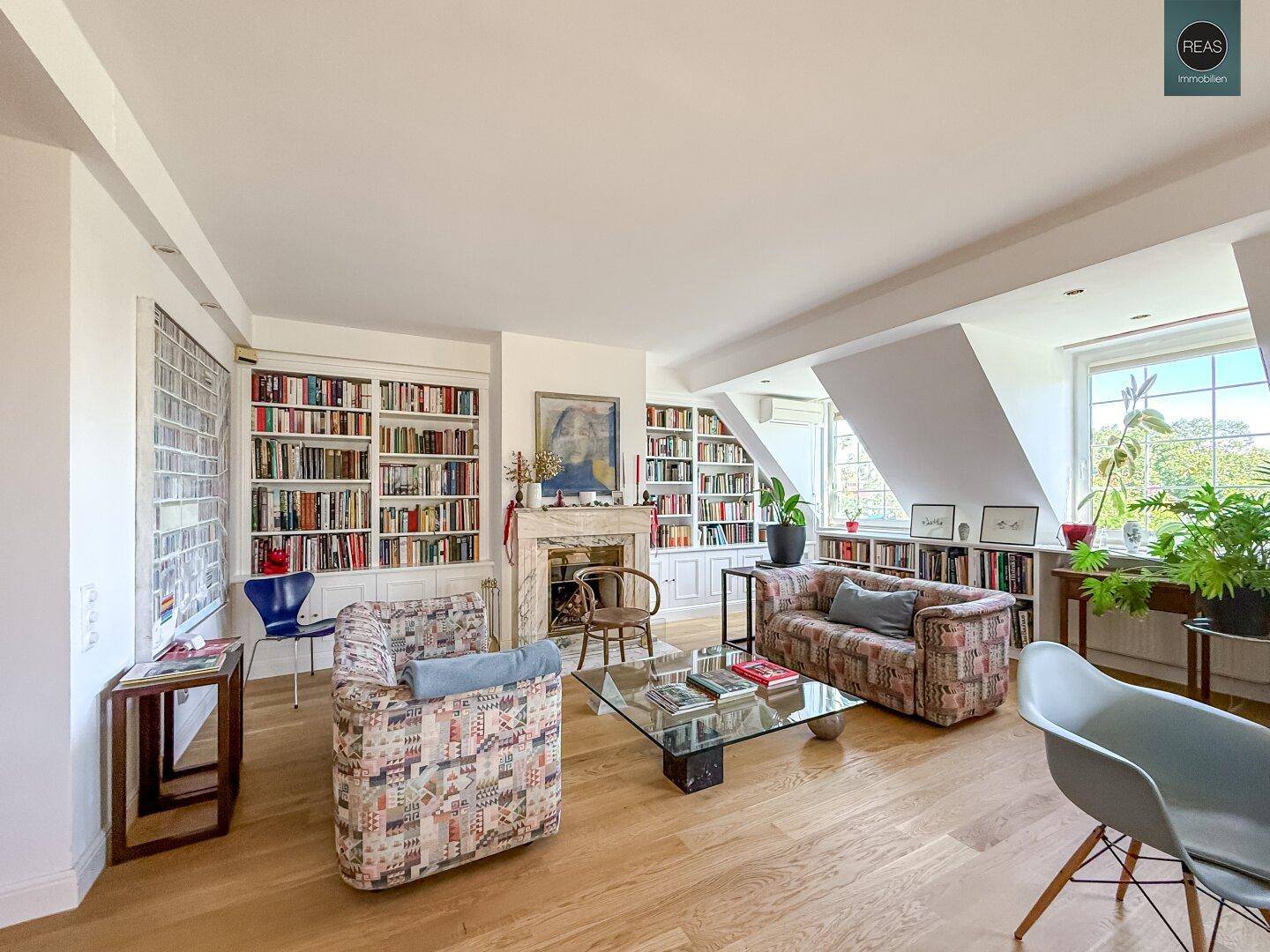 Heller Wohnbereich mit bequemen Sofas, Holzboden und umfangreichen Bücherregalen.