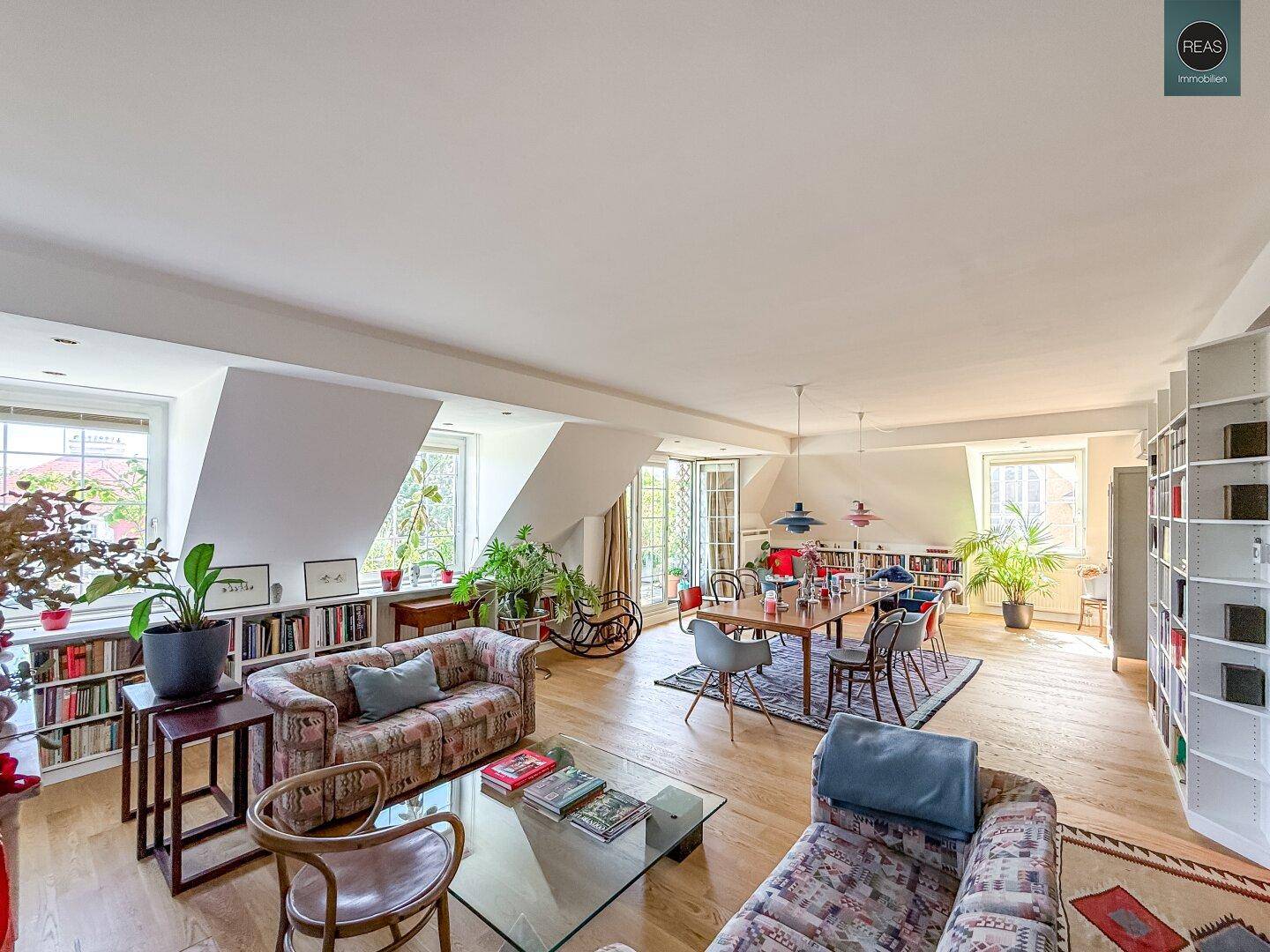 Weitläufiger Wohn- und Essbereich mit Holzboden, vielen Pflanzen und Zugang zur Terrasse.