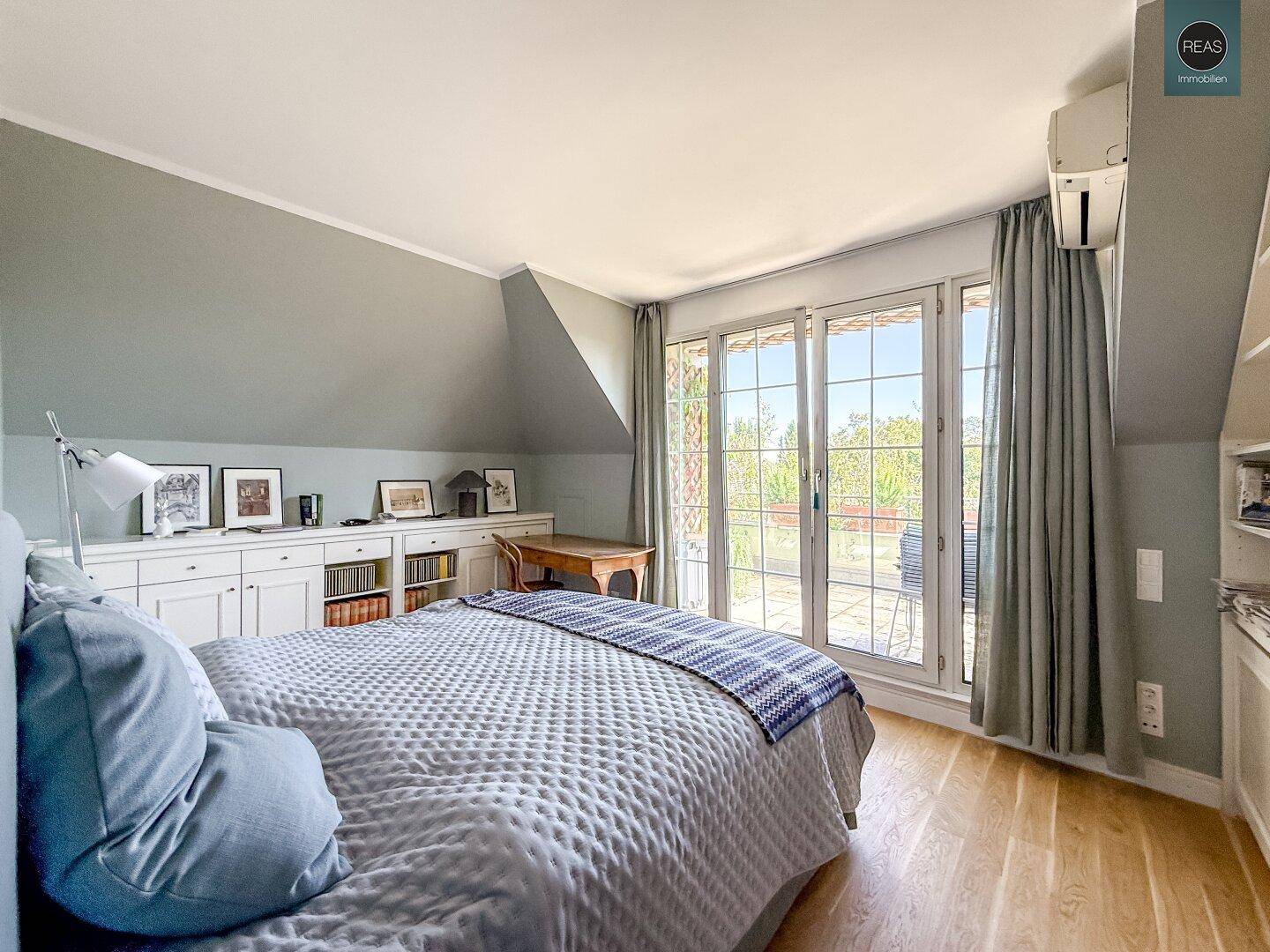 Gemütliches Schlafzimmer mit Holzboden, Bett und Zugang zu einer sonnigen Terrasse.