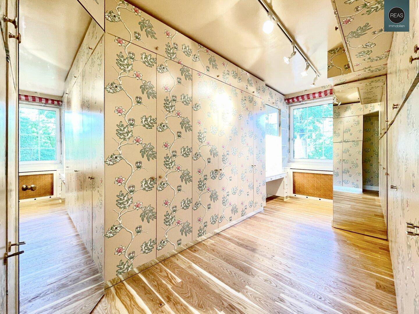 Charmantes Zimmer mit Holzboden und floral gemusterten Einbauschränken, die viel Stauraum bieten.