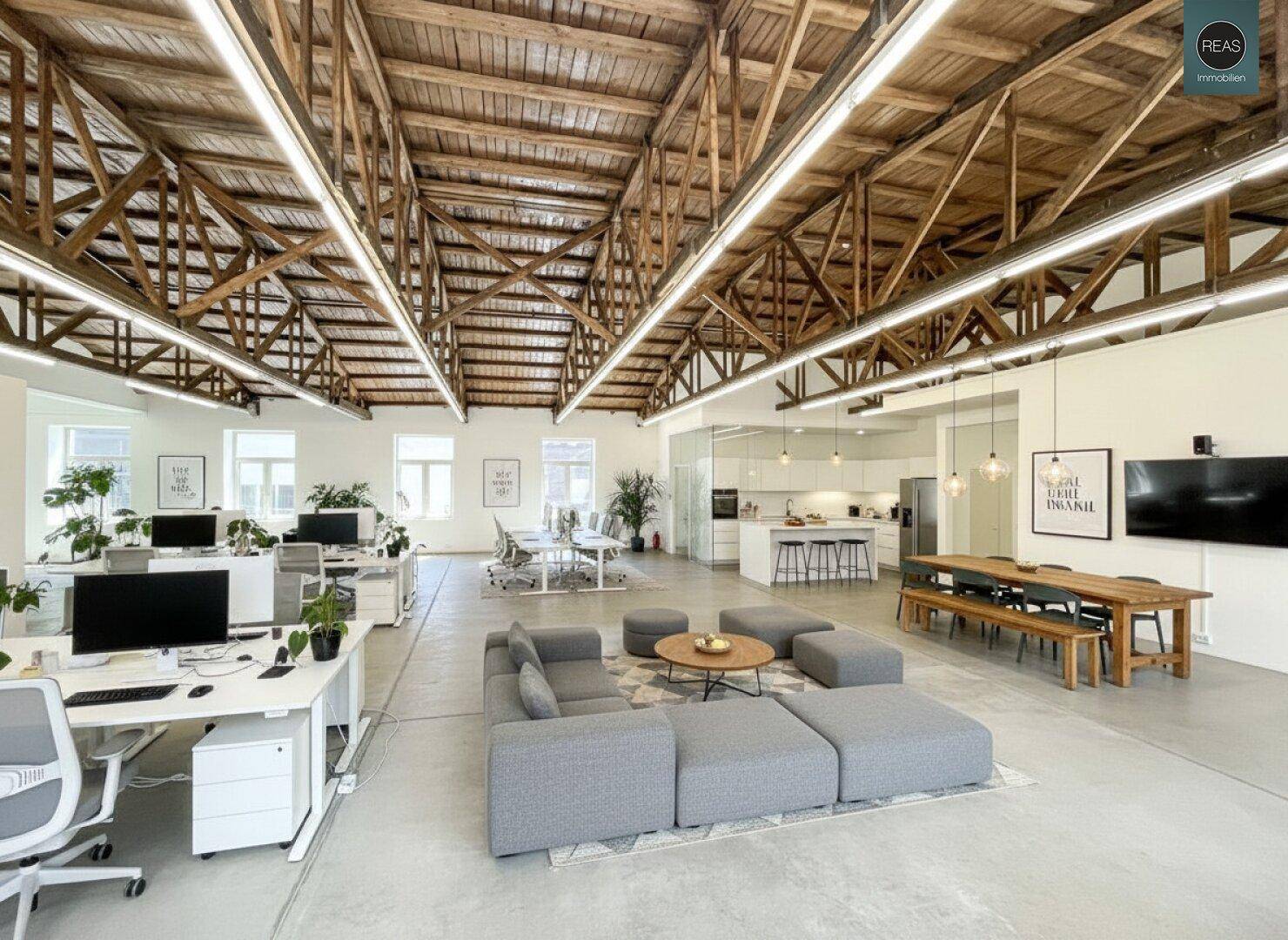 Offener Bürobereich mit Arbeitsplätzen, Lounge-Ecke, Essbereich und moderner Küche.