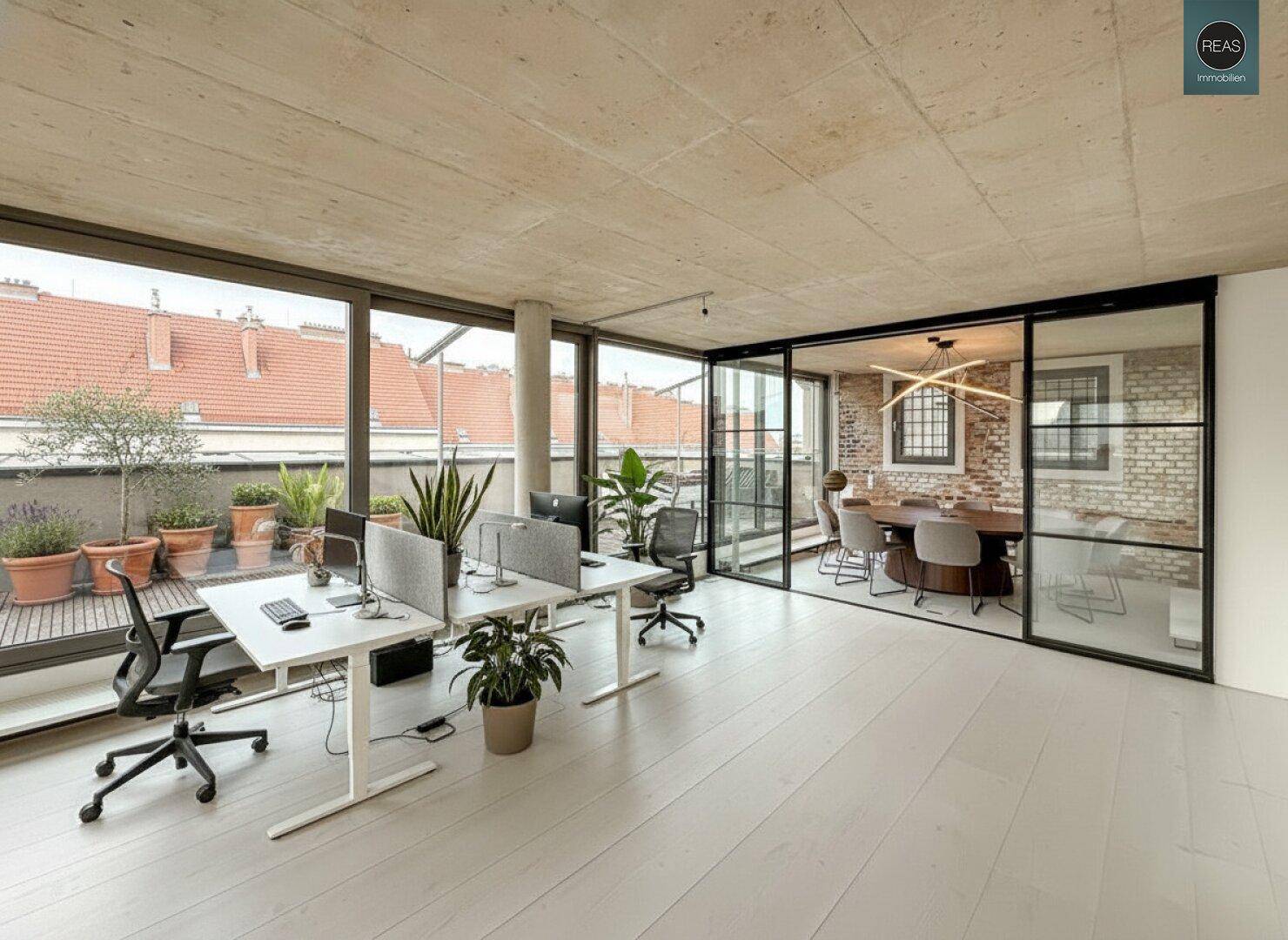 Moderner Bürobereich mit Pflanzen, Schreibtischen und einem Konferenzraum hinter eleganten Glaswänden.