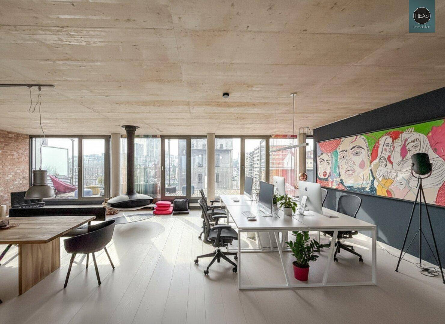 Moderner Bürobereich mit Schreibtischen, Kunst an der Wand und einem Hängekamin, der eine gemütliche Atmosphäre schafft.
