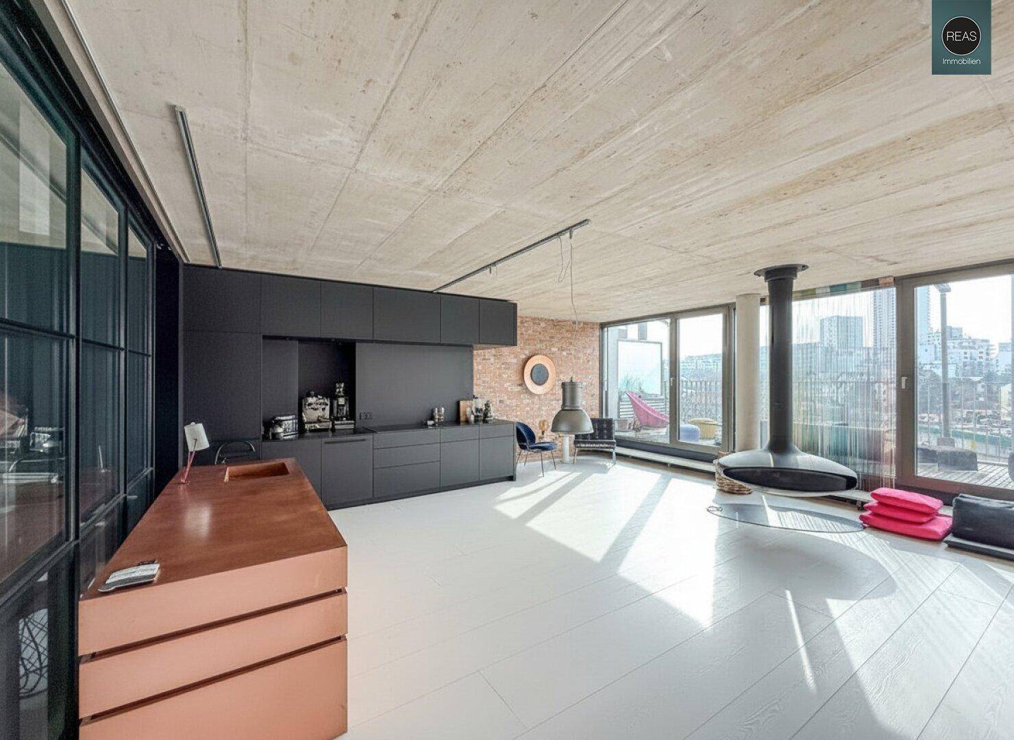 Geräumiger Loft-Raum mit schwarzer Küchenzeile, Holzboden und Hängekamin, der eine moderne Ästhetik bietet.