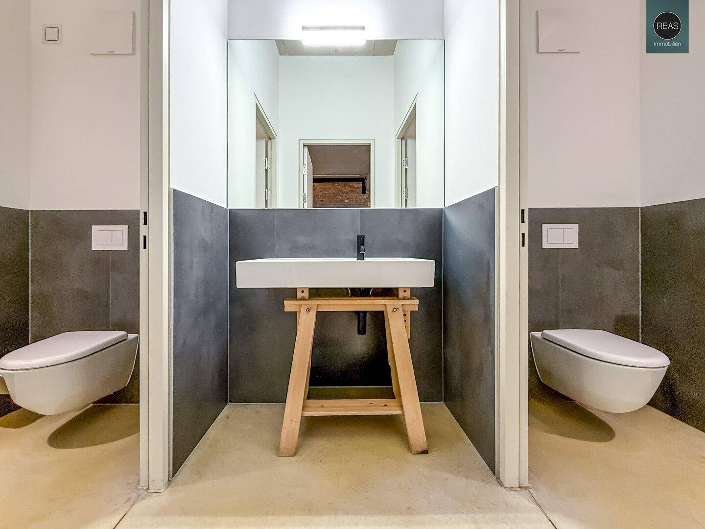 Modernes Badezimmer mit zwei wandhängenden Toiletten und einem stilvollen Waschbecken.
