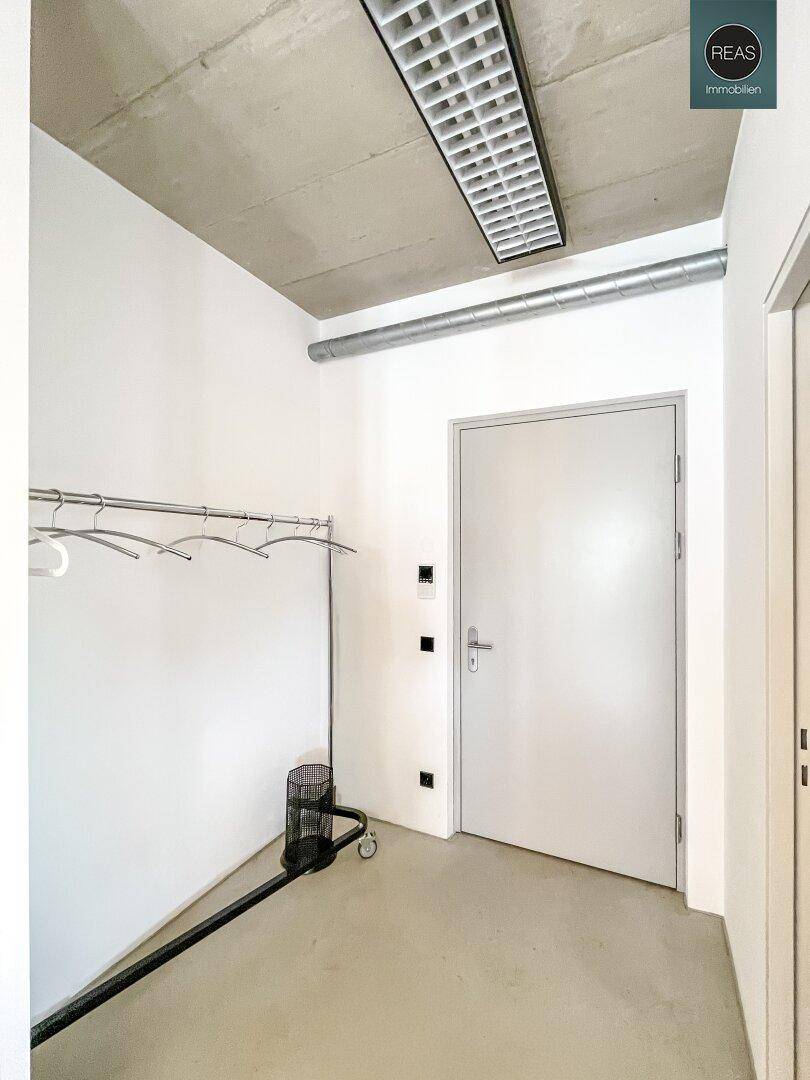 Heller Flur mit Garderobenstange und moderner Deckenbeleuchtung.