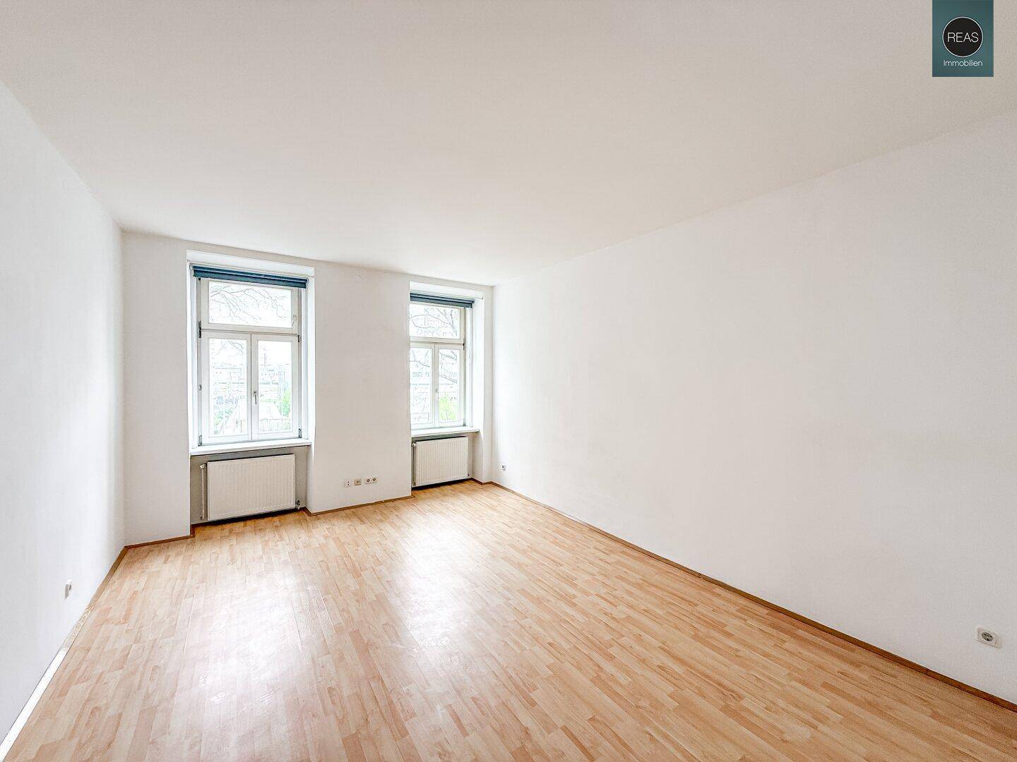 Geräumiger, unmöblierter Raum mit Holzboden und großen Fenstern, ideal für verschiedene Nutzungen.