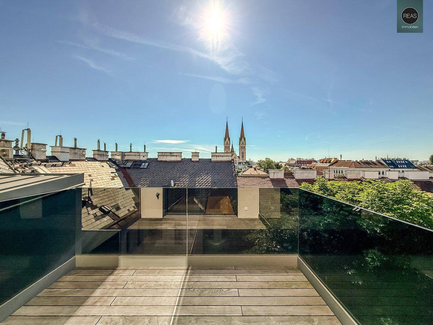 Sonniger Außenbereich mit Holzboden und Glasgeländer, ideal für Entspannung im Freien.
