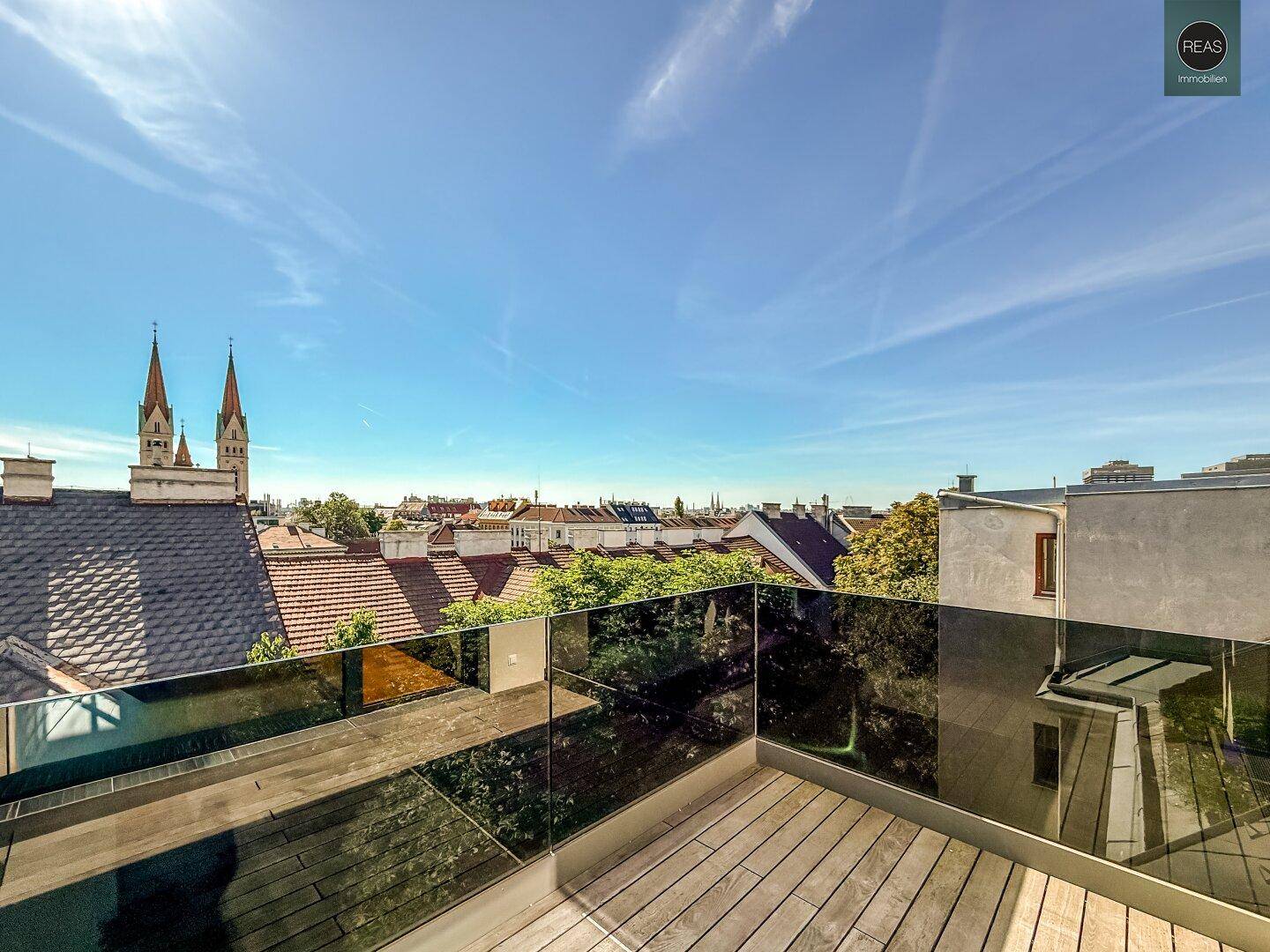 Dachterrasse mit Holzboden und Glasgeländer bietet weiten Blick über die Stadt.