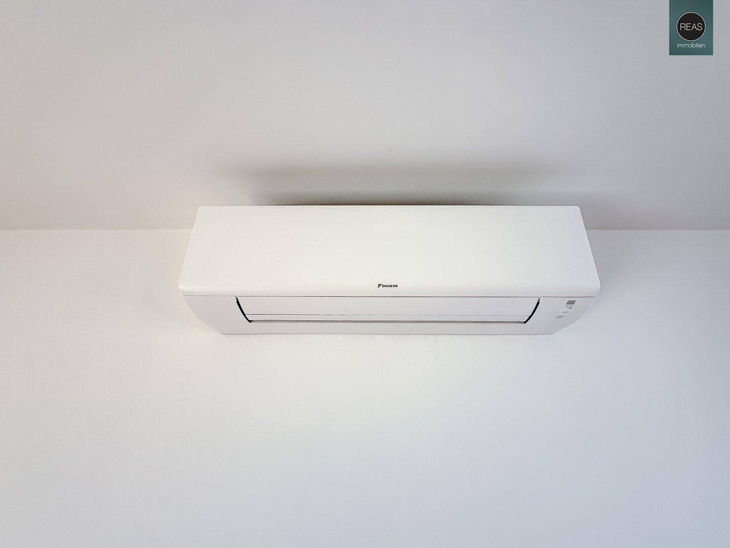Weiße Klimaanlage an einer schlichten weißen Wand montiert.