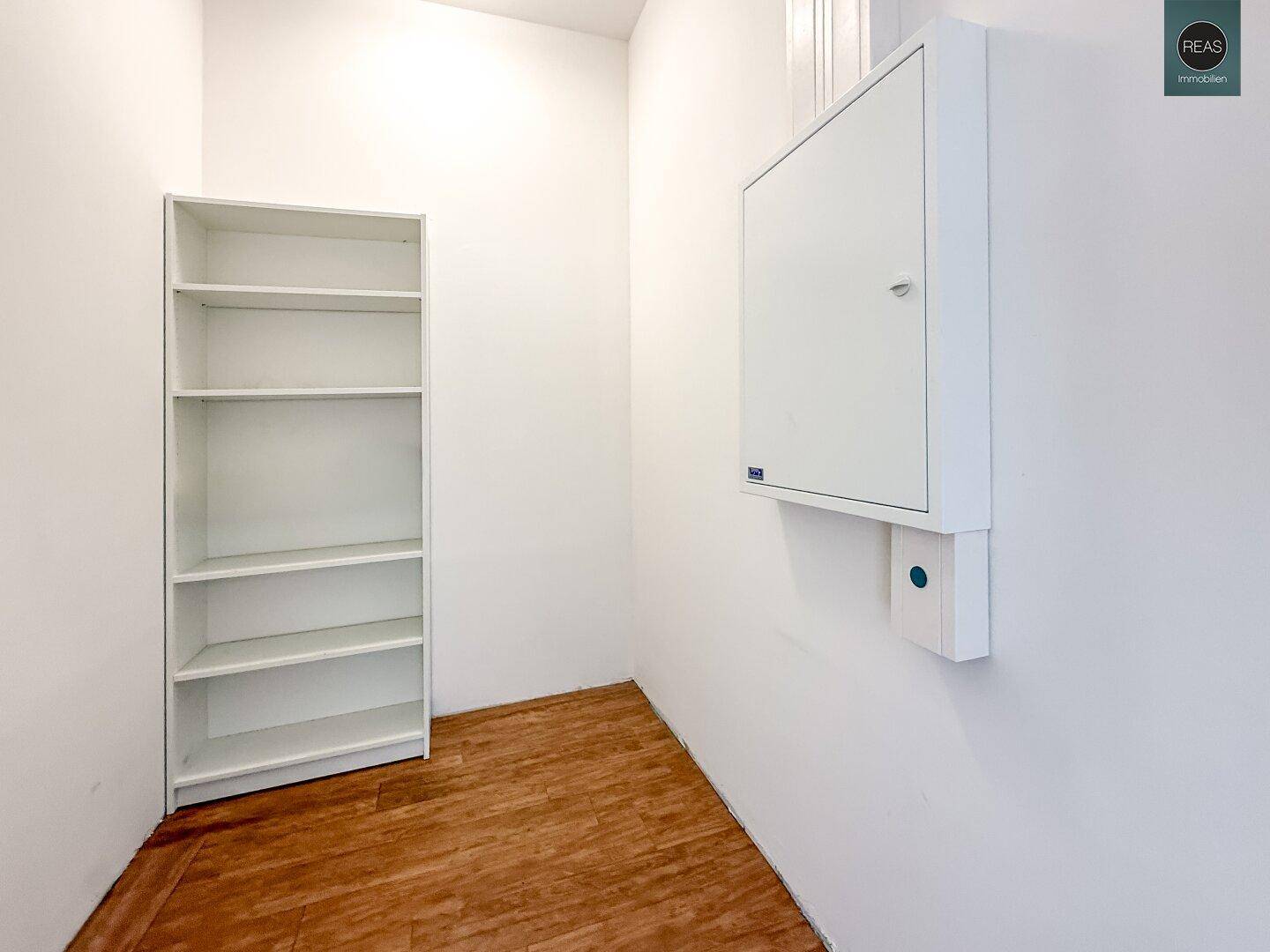 Kleiner Abstellraum mit einem weißen Regal und einem an der Wand montierten Elektroschrank.