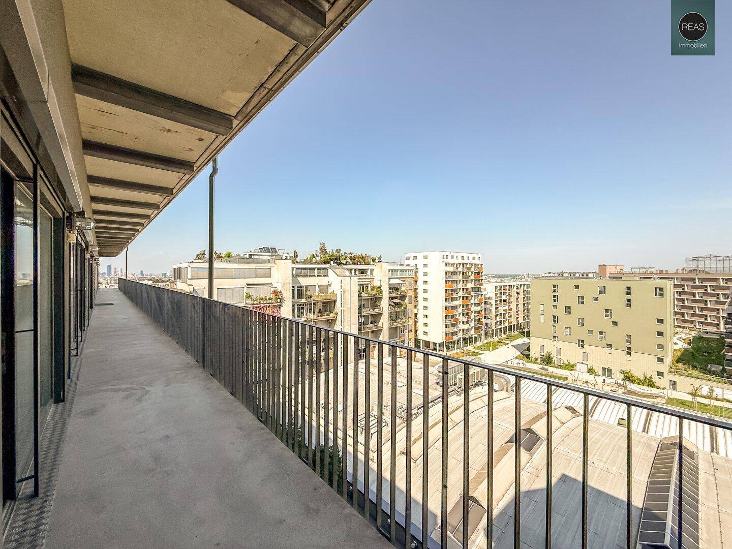 Langer Außenkorridor oder Balkon mit Metallgeländer und Blick auf umliegende Gebäude.