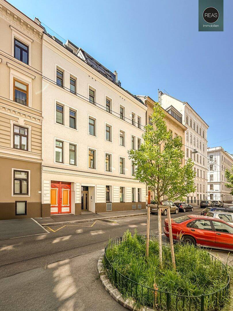 Historisches Wohngebäude an einer belebten Stadtstraße mit parkenden Autos.
