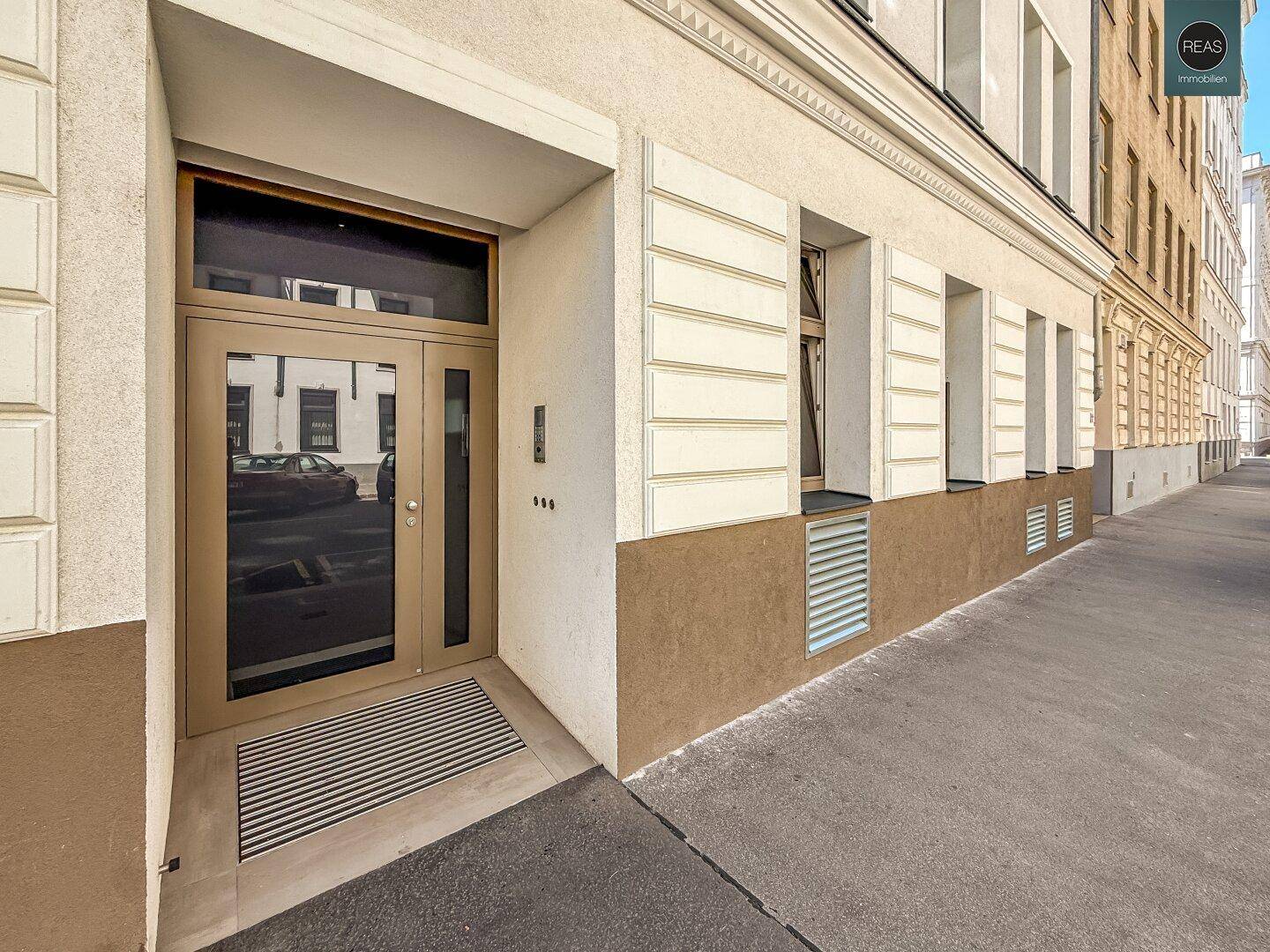 Moderner Eingangsbereich eines Wohnhauses an einer städtischen Straße.