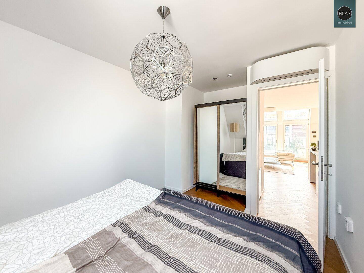 Schlafzimmer mit Holzboden und Schiebetür, die zum offenen Wohnbereich führt.