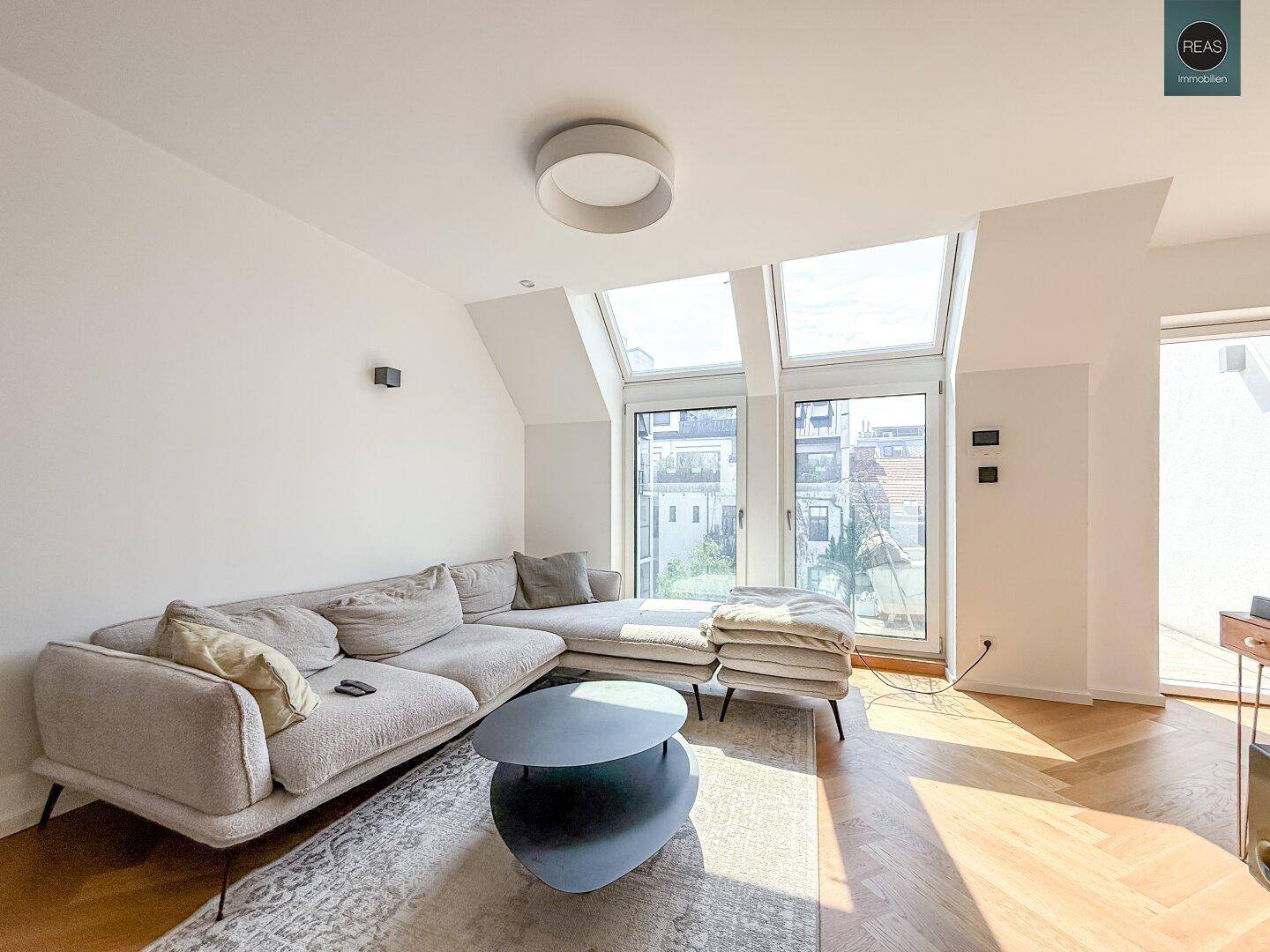 Helles Wohnzimmer mit beigem Sofa, Holzboden und großen Dachfenstern für eine freundliche Atmosphäre.