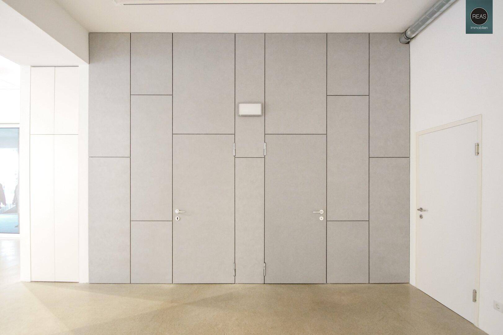 Moderne Wandverkleidung mit integrierten Türen in einem hellen Flurbereich.