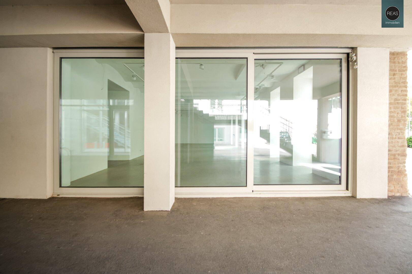 Große Glasfronten eines modernen Gebäudes, die den Blick ins helle Innere freigeben.