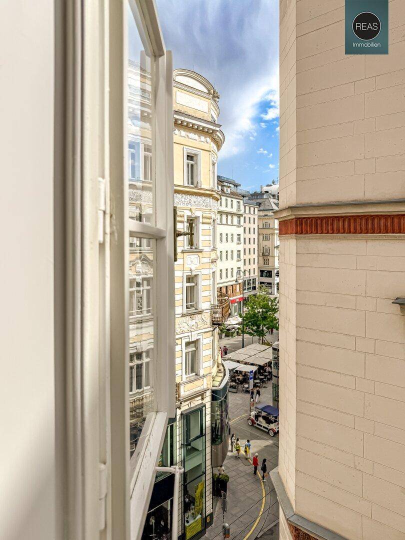 Vertikaler Blick aus dem Fenster auf die Fassaden der historischen Gebäude und das Straßengeschehen.