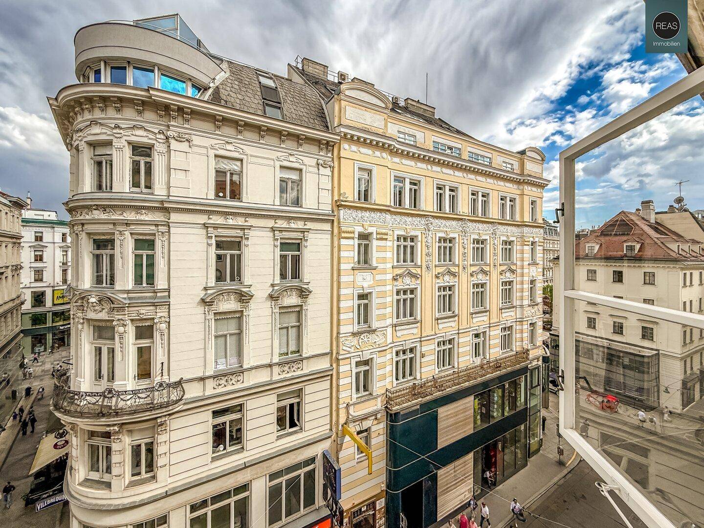 Blick aus dem Fenster auf die belebte Stadtstraße mit historischen Gebäuden und Geschäften.