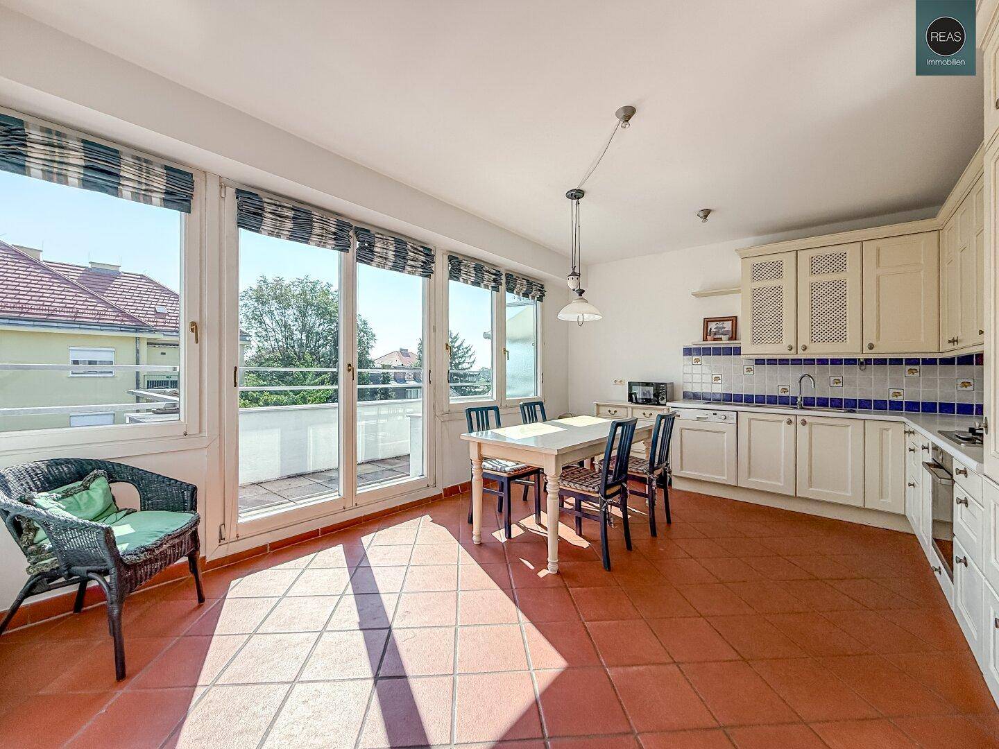 Helle Wohnküche mit Terracottaboden, traditionellen Schränken und Zugang zur Terrasse.