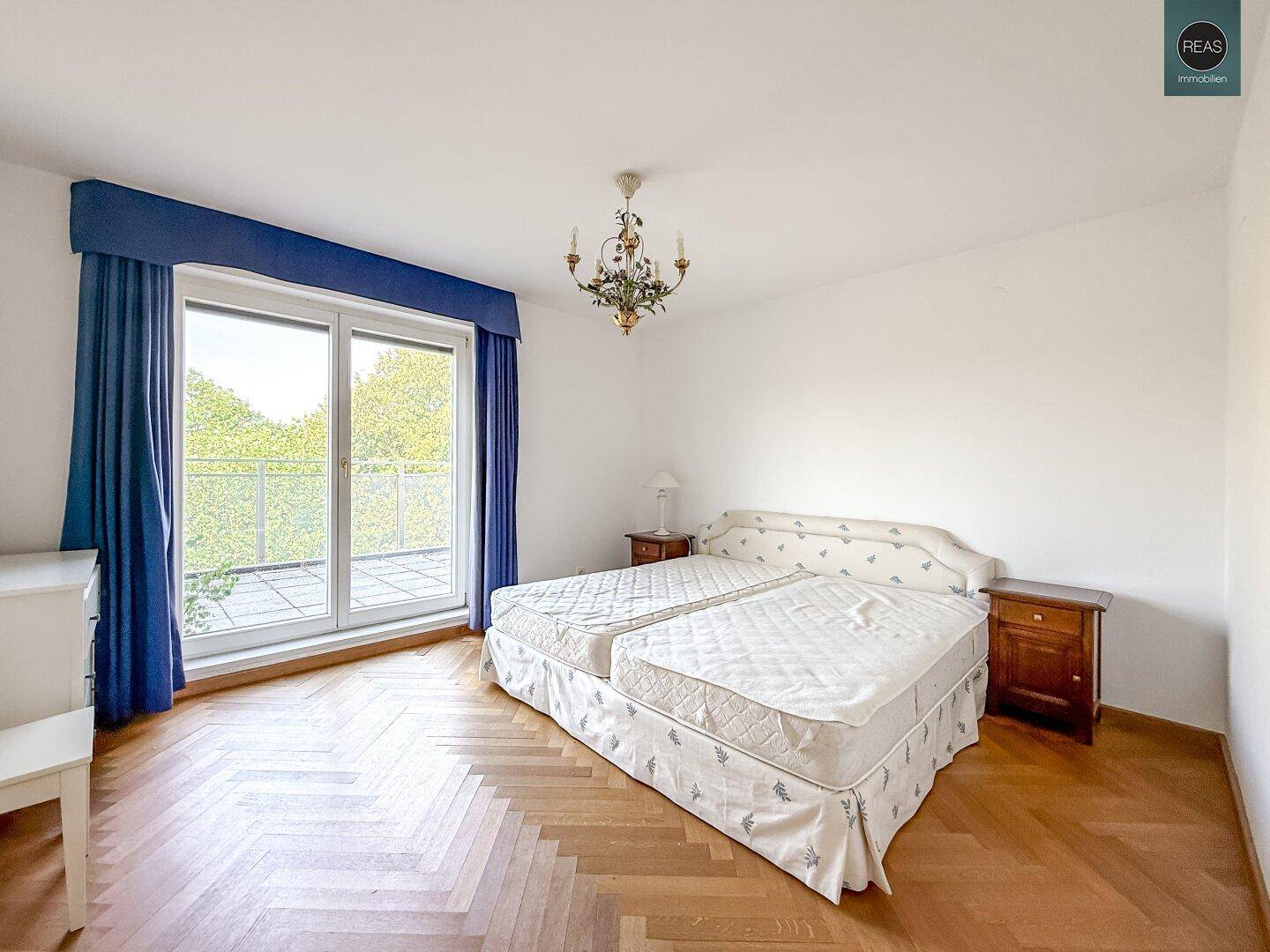 Geräumiges Schlafzimmer mit Doppelbett, Parkettboden und Zugang zum Balkon.