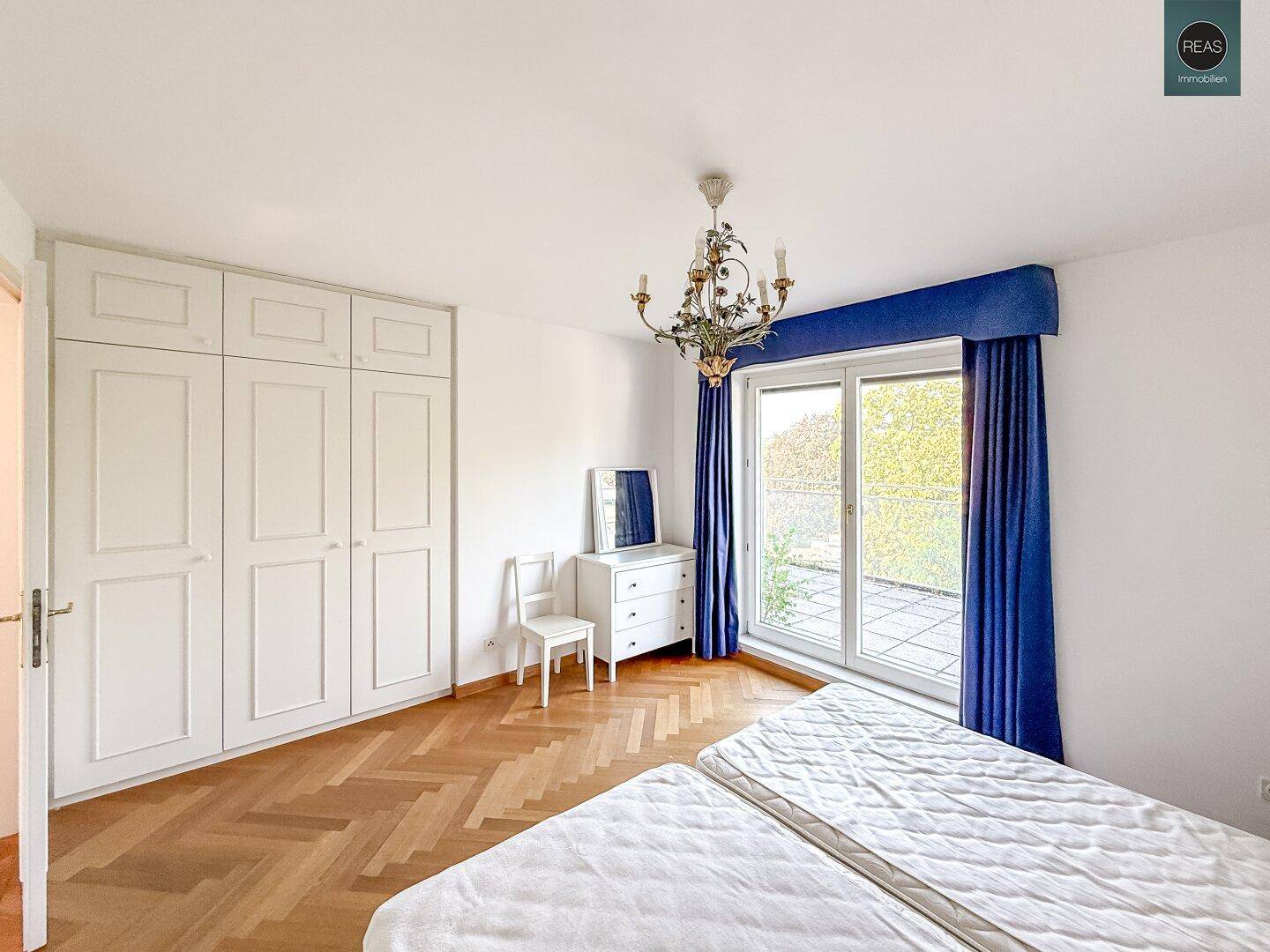 Schlafzimmer mit Doppelbett, Einbauschränken und Zugang zu einem Außenbereich.