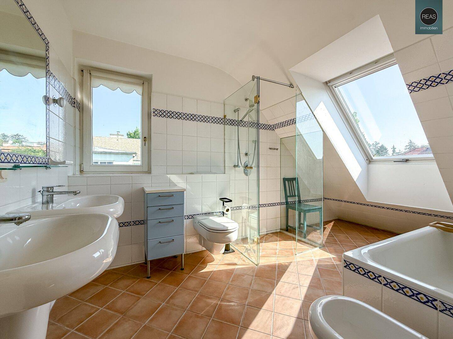 Helles Badezimmer mit Dachschrägen, zwei Waschbecken, Dusche und Badewanne.