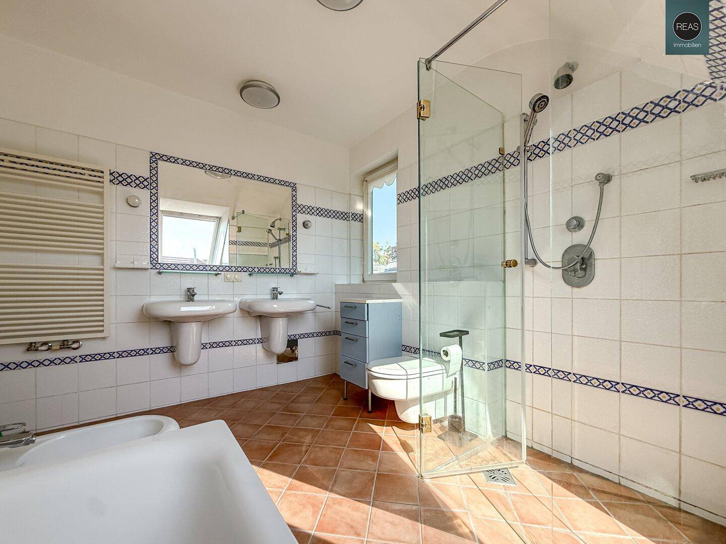 Geräumiges Badezimmer mit zwei Waschbecken, Dusche, Badewanne und beheiztem Handtuchhalter.