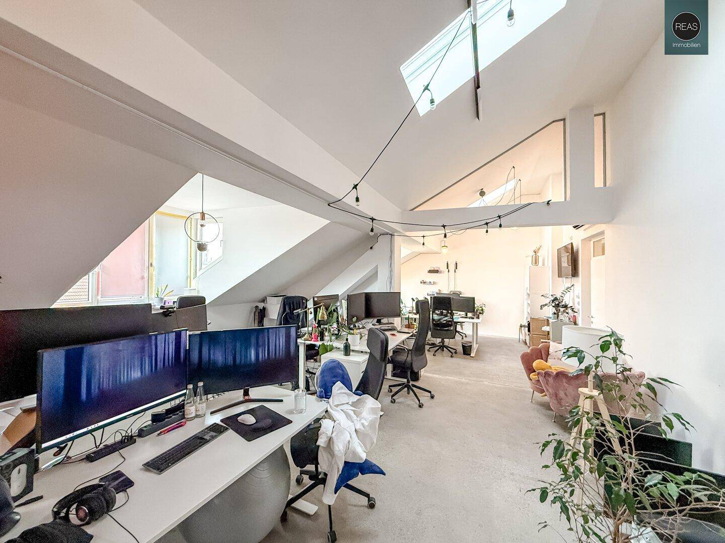 Heller Bürobereich mit mehreren Arbeitsplätzen, Dachfenstern und moderner Einrichtung.
