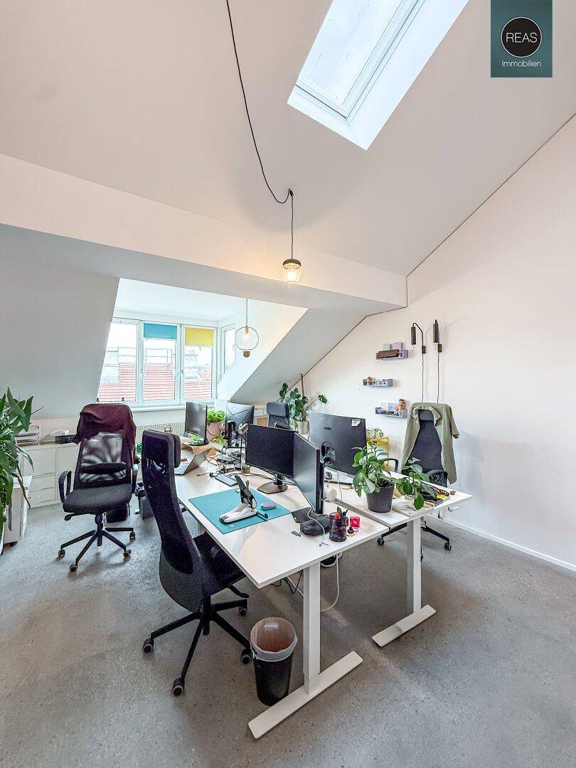 Moderner Arbeitsplatz in einem hellen Büro mit Dachfenster und minimalistischer Einrichtung.