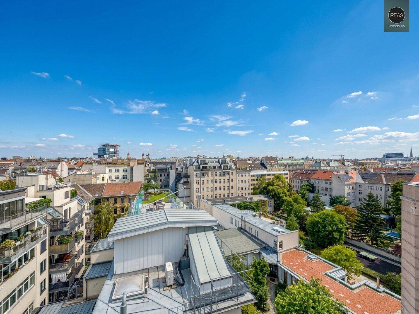 Panoramablick über die Stadt mit zahlreichen Gebäuden und grünen Baumkronen.