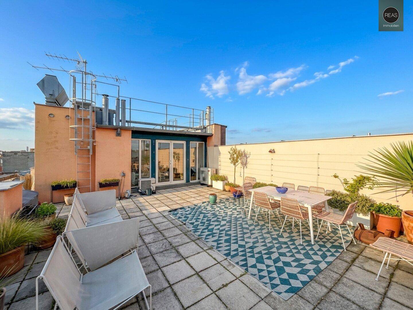 Dachterrasse mit Außenbereich, Sitzgelegenheiten und Blick auf die umliegenden Gebäude.