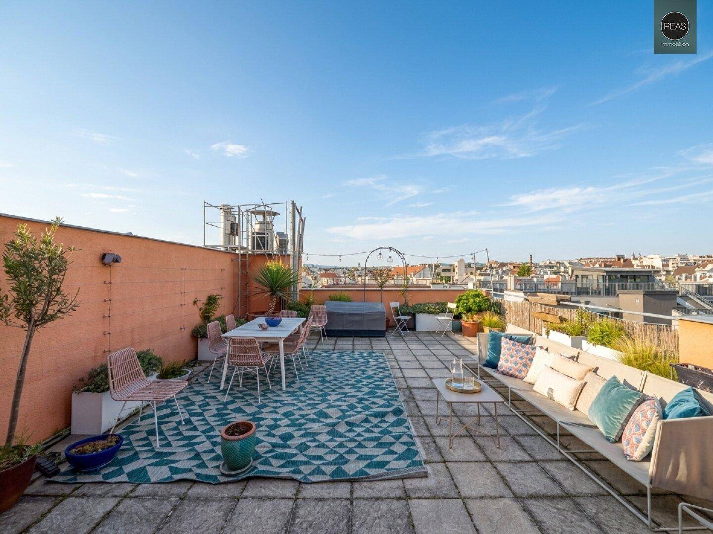 Weitläufige Dachterrasse mit Sitzgelegenheiten, Pflanzen und Panoramablick über die Stadt.