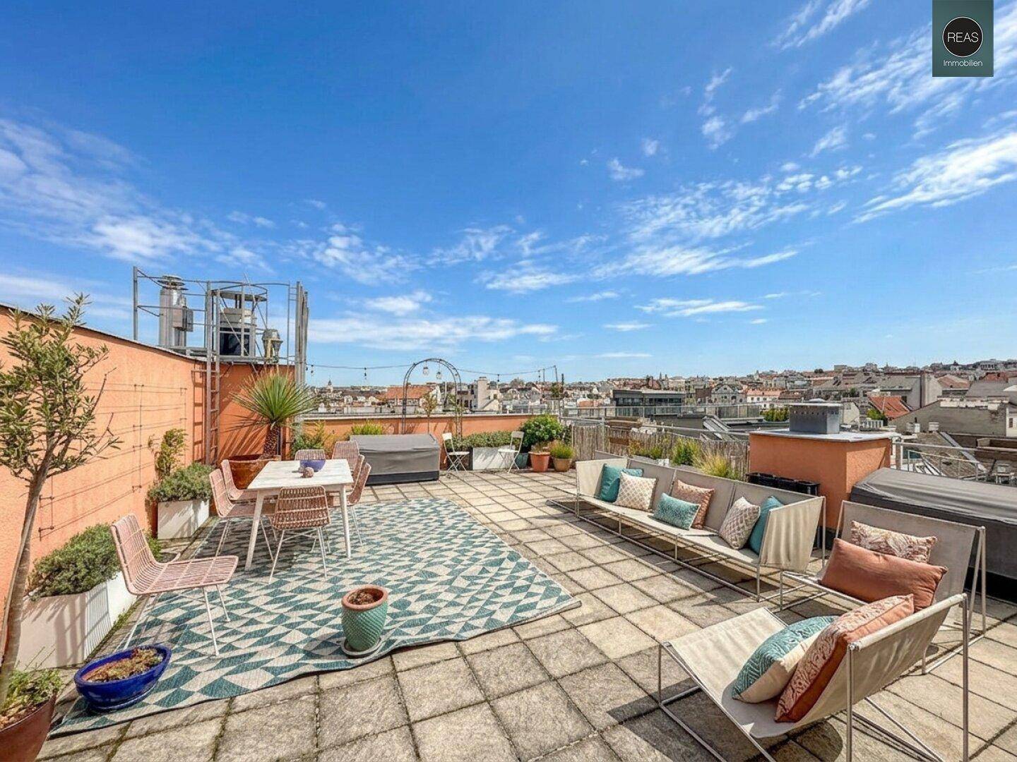 Geräumige Dachterrasse mit Sitzgelegenheiten, Pflanzen und weitem Blick über die Stadt.