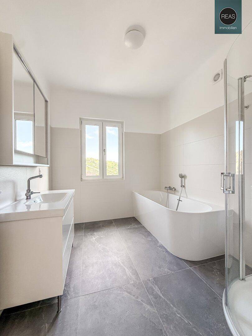 Modernes Badezimmer mit freistehender Badewanne, Duschkabine und Fenster für natürliche Belüftung.