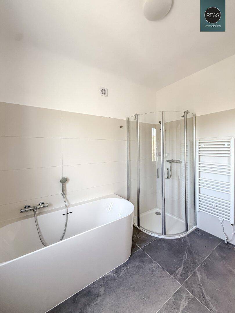 Modernes Badezimmer mit Duschkabine, freistehender Badewanne und Handtuchheizkörper.