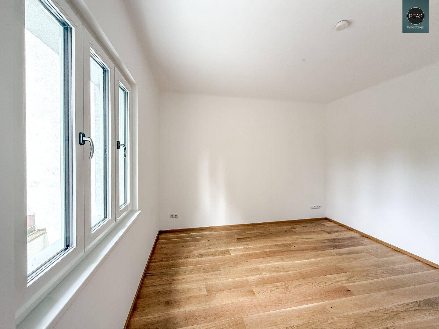 Geräumiges Zimmer mit Eichenparkettboden und großen Fenstern, die viel Licht hereinlassen.