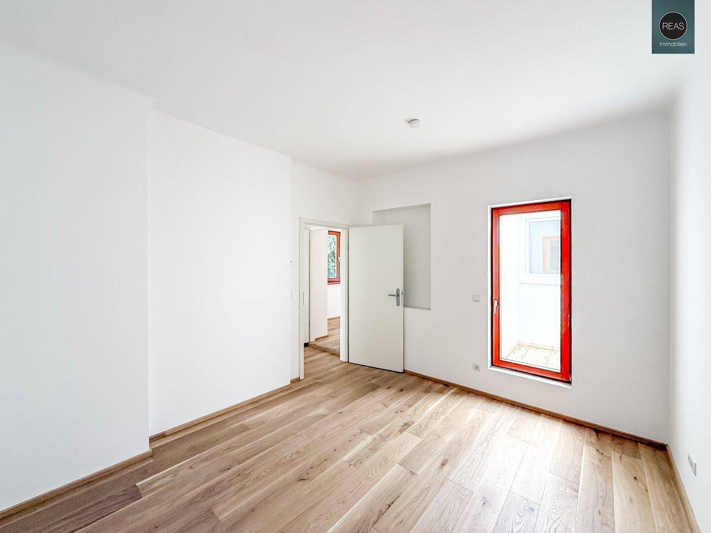 Geräumiges Schlafzimmer mit Holzboden und Zugang zu weiteren Räumen.