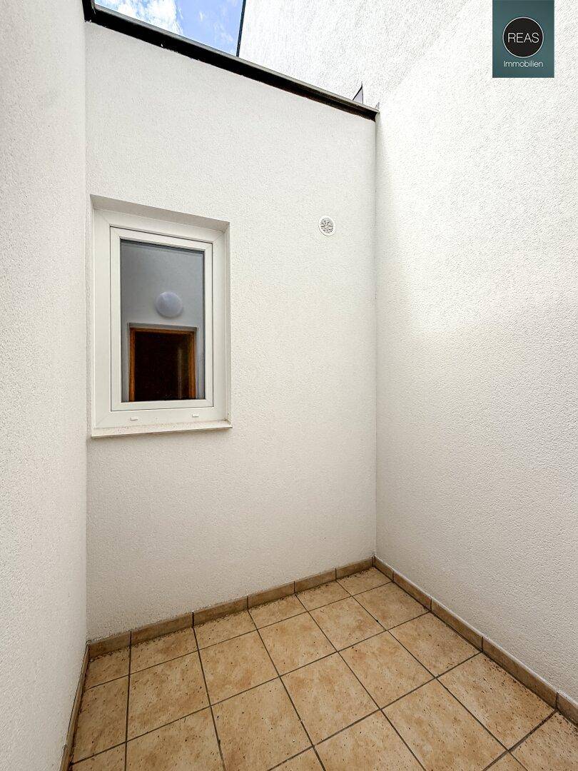 Kleiner Raum mit Fliesenboden und Fenster, möglicherweise ein Abstellraum.