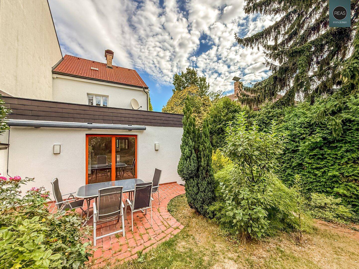 Rückseite des Hauses mit großer Terrasse und Garten, ideal für Entspannung im Freien.