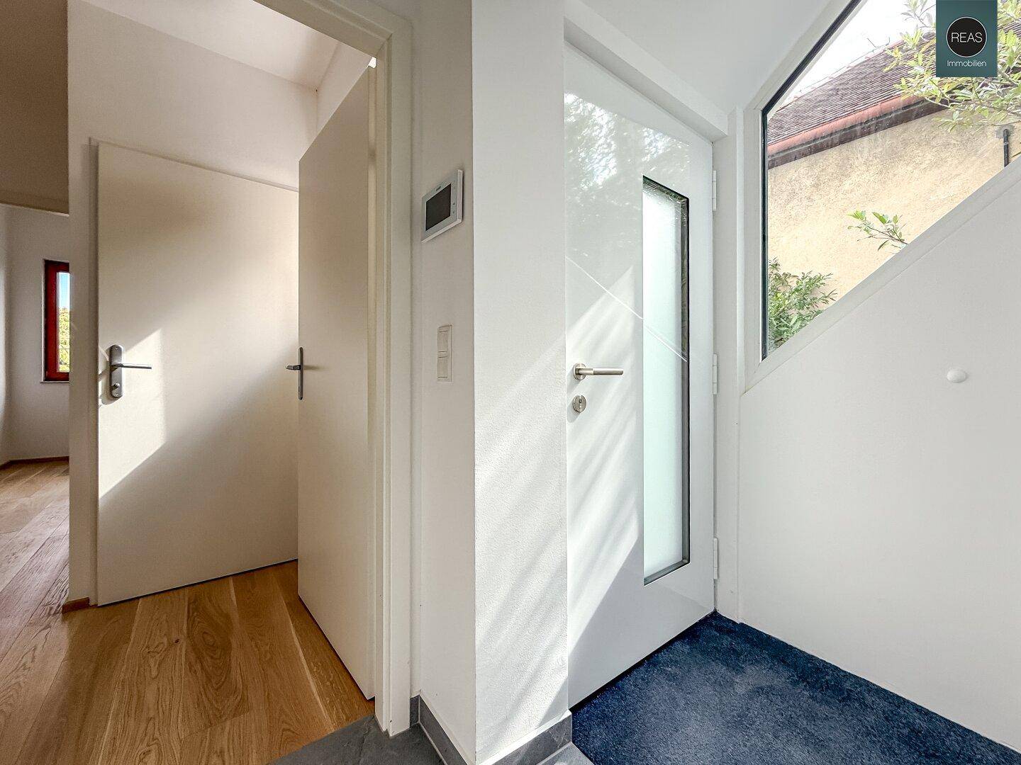 Heller Eingangsbereich mit moderner Tür und Holzboden.