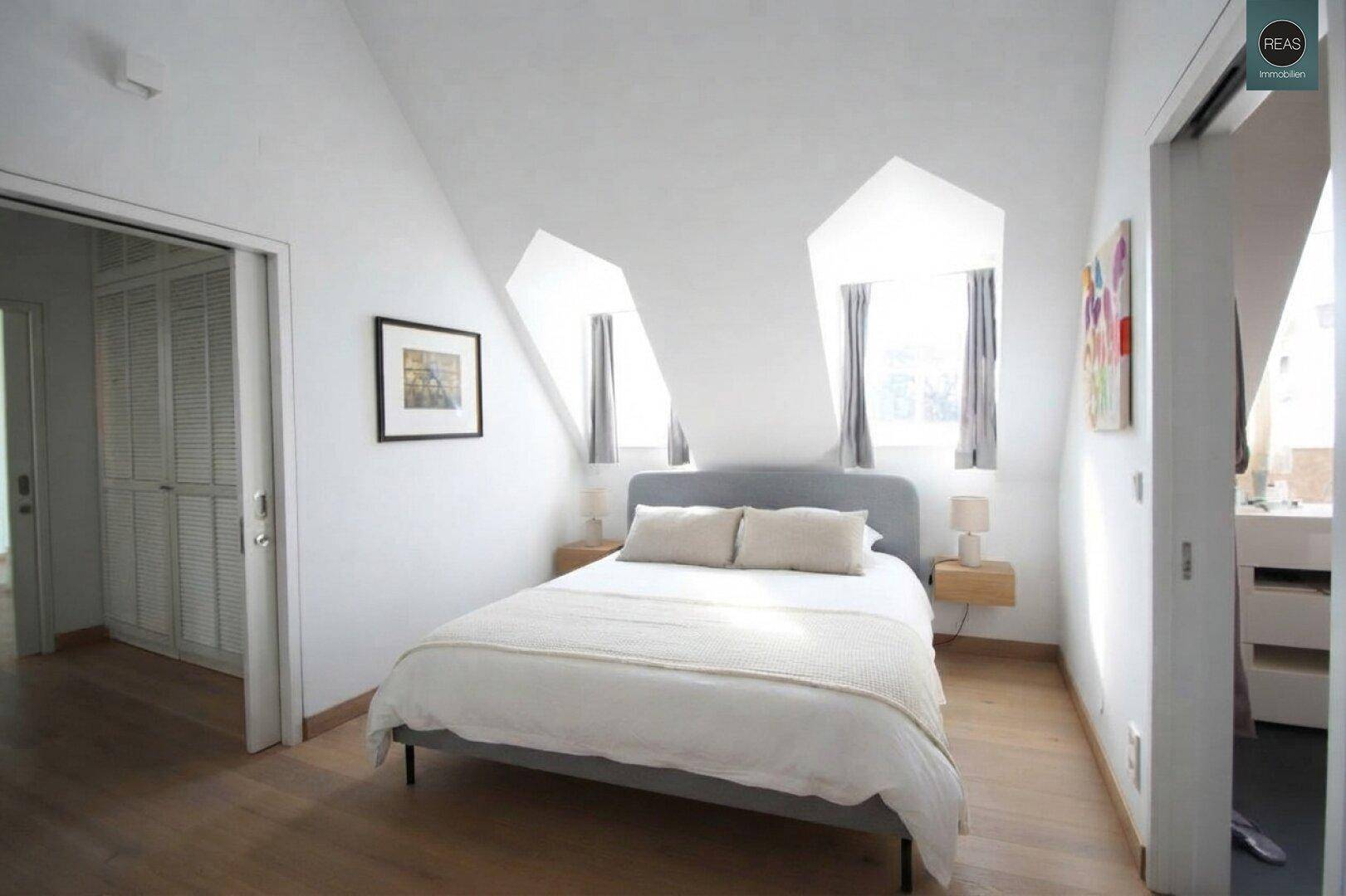 Helles Schlafzimmer im Dachgeschoss mit Doppelbett, Dachschrägen und Holzboden.
