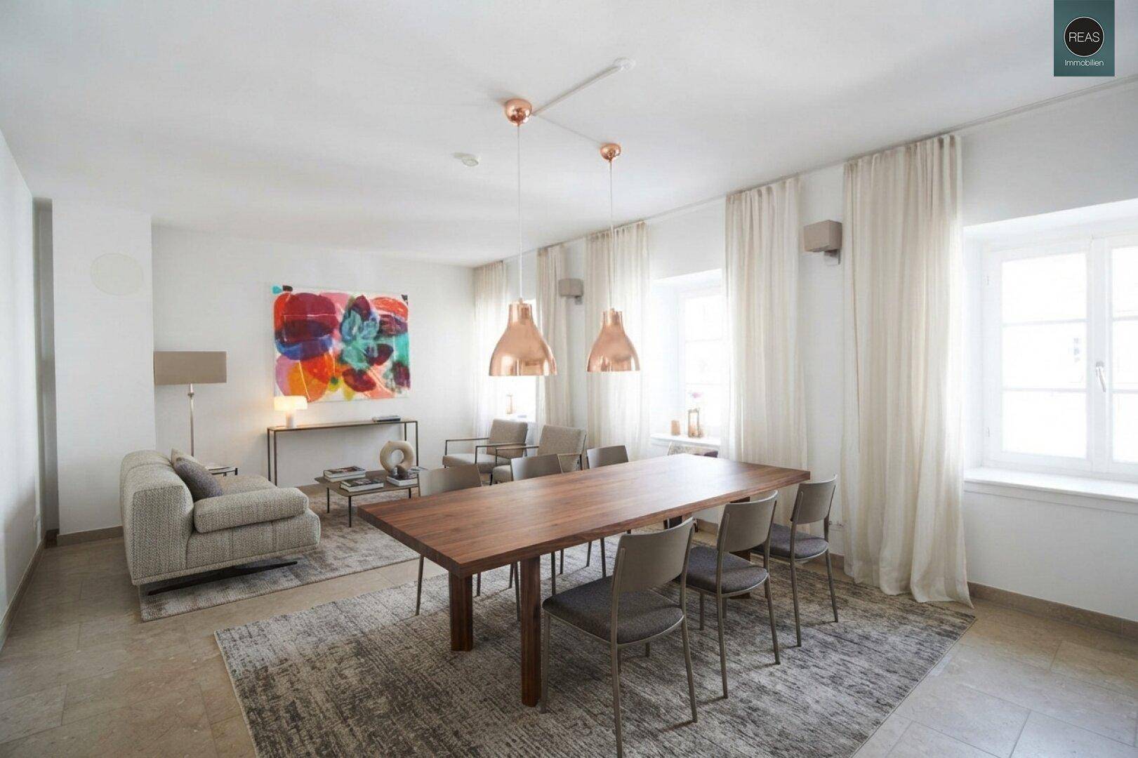 Heller Wohn- und Essbereich mit modernem Esstisch, bequemer Couch und farbenfroher Kunst.