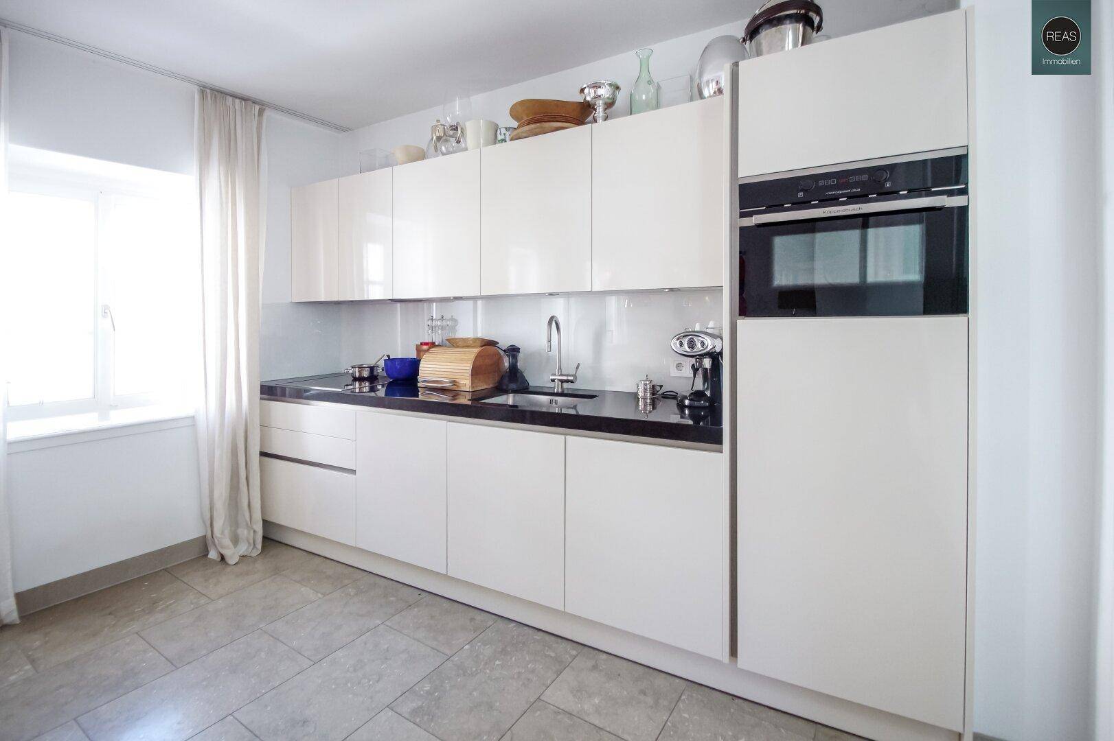 Detailansicht der modernen Einbauküche mit weißen Hochglanzschränken und integriertem Backofen.
