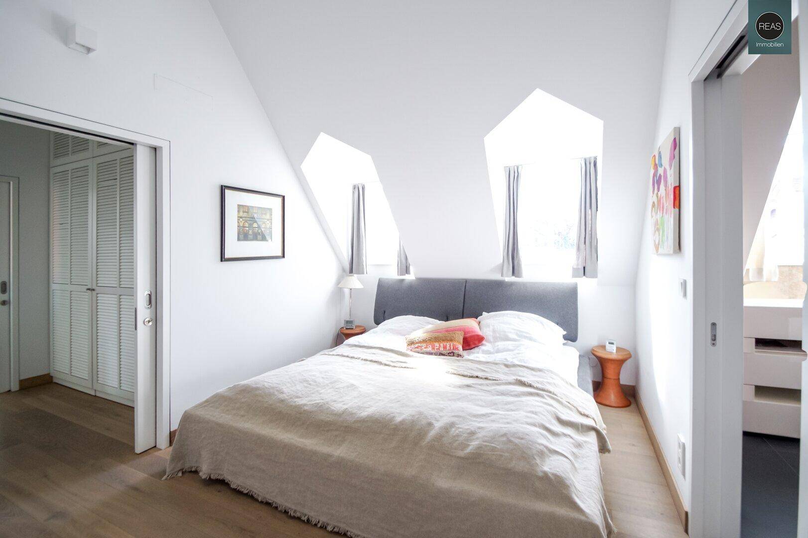 Gemütliches Schlafzimmer im Dachgeschoss mit Doppelbett, Dachschrägen und Holzboden.
