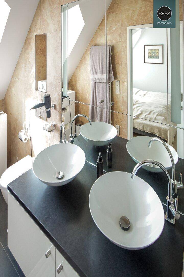 Elegantes Badezimmer mit zwei Aufsatzwaschbecken, großem Spiegel und Badewanne.