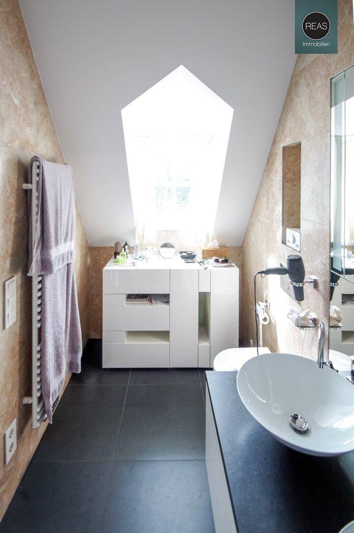 Helles Badezimmer im Dachgeschoss mit Dachfenster, Heizkörper und modernem Waschtisch.