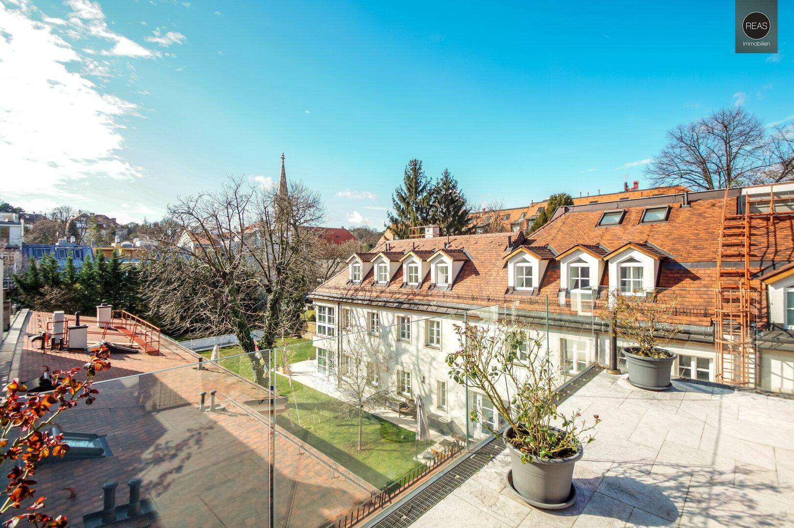 Weitläufige Dachterrasse mit Blick auf die umliegenden Gebäude und grüne Umgebung.