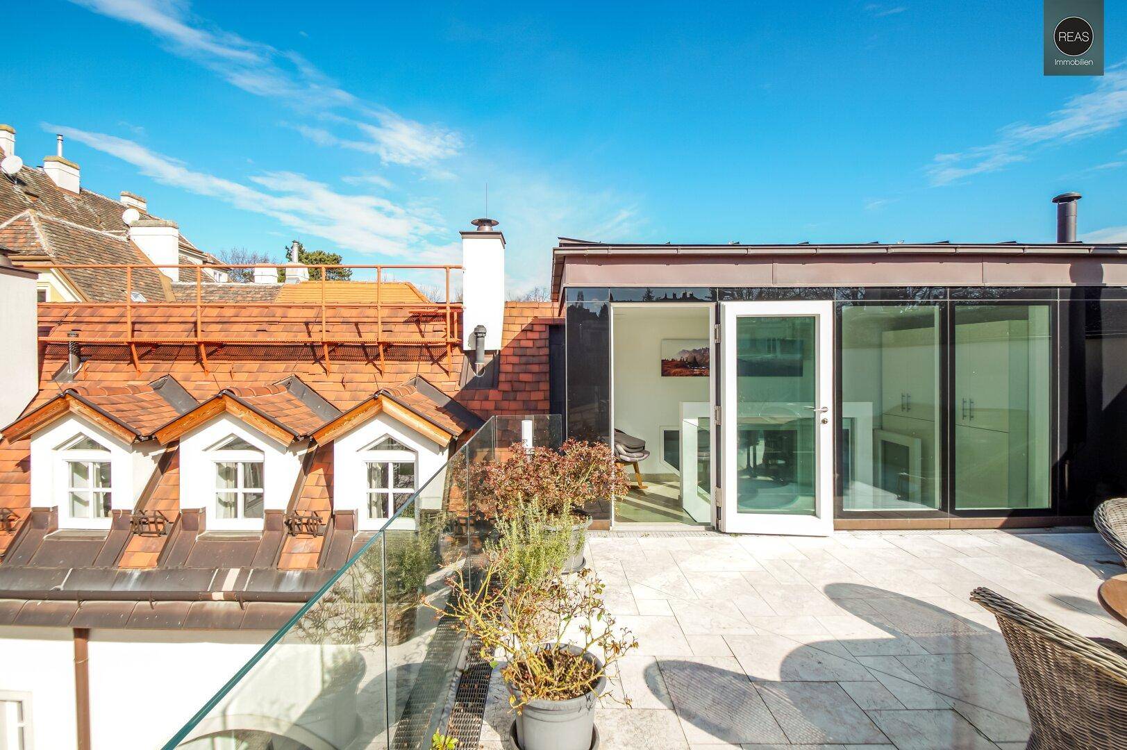 Große Dachterrasse mit Zugang zu einem modernen Anbau und weitem Ausblick.